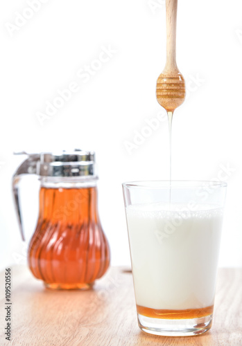hot milk with honey, honey jar and honey dipper on white backgro