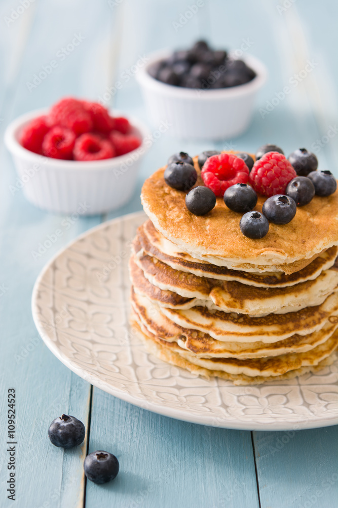 Pancakes with blueberries and raspberry on blue wood background 
