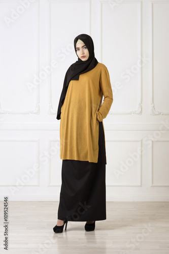 Studio photo of a beautiful young woman eastern type full-length, on a light background, dressed in the Muslim style