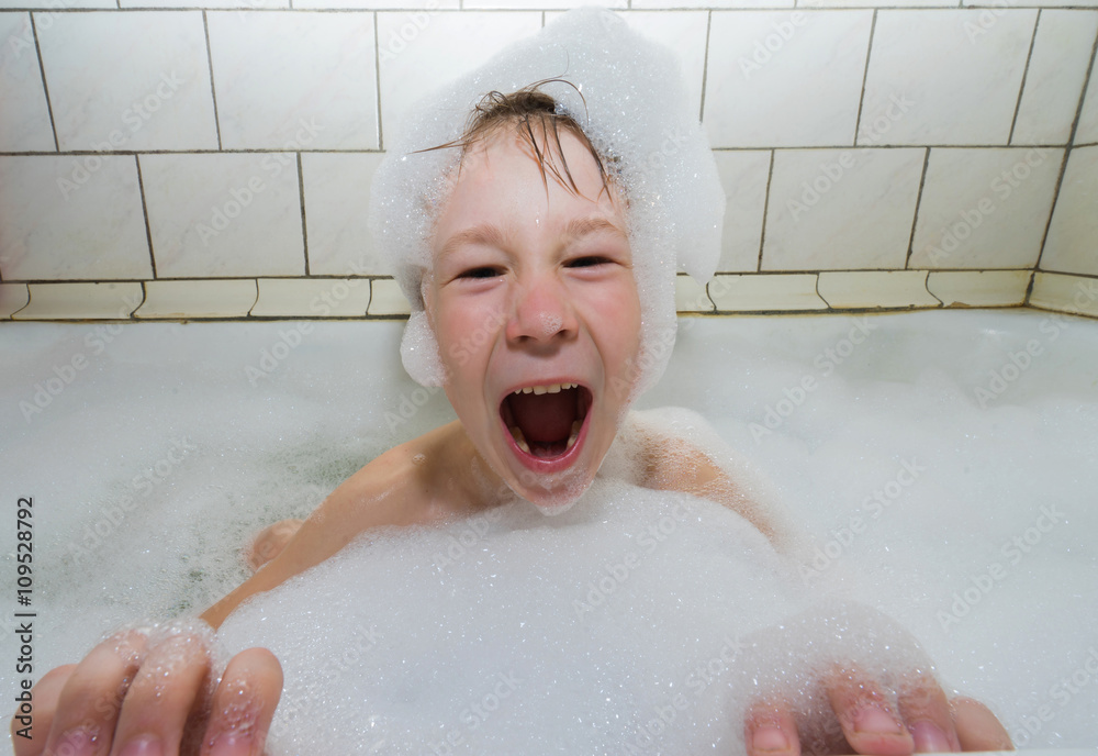 Little boy in a cap of foam soap happy screaming in the bathroom . Little boy in a cap of foam soap happy screaming in the bathroom .