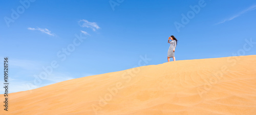Young woman standing and looking at sand dune desert landscape. Banner.