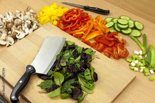 Cleaver knife laying on top of some freshly cut babyleaf salad