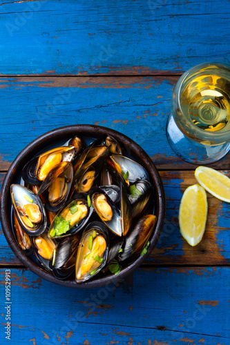 Mussels in clay bowl, glass of white wine and lemon photo