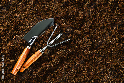 Gardening tools on plain soil. Image taken from above, top view. Advertising background with ample copy space.