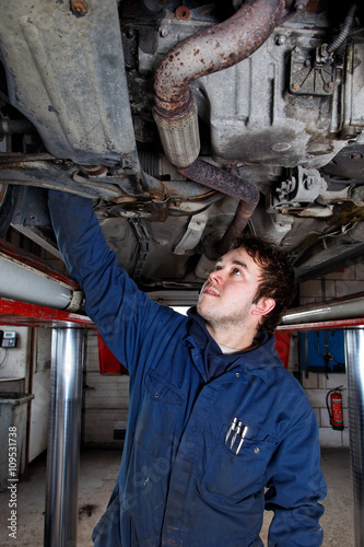 young auto mechanic checking a car under hydraulic platform © breedfoto