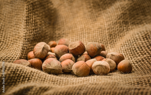 Natural, unbroken hazelnuts on a jute bag background. Closeup photo with vintage postprocessing. Horizontal image.