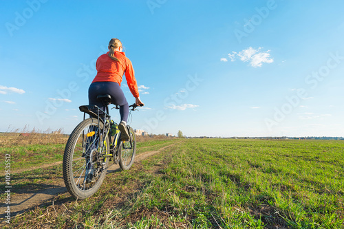 Bike riding - Young woman trying to ride on a bicycle in nature offroad