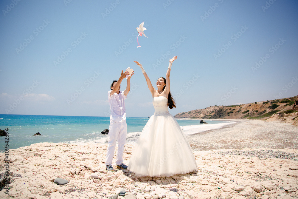Happy smiling bride and groom hands releasing white doves on a sunny day. Mediterranean Sea. Cyprus Happy smiling bride and groom hands releasing white doves on a sunny day. Mediterranean Sea. Cyprus