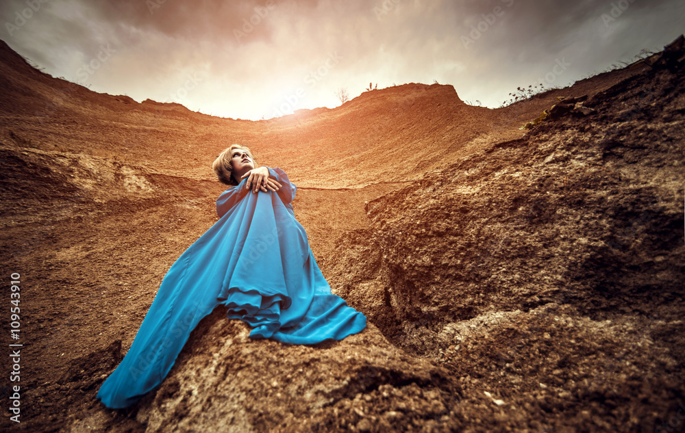 Woman in long blue dress on the sand canyon