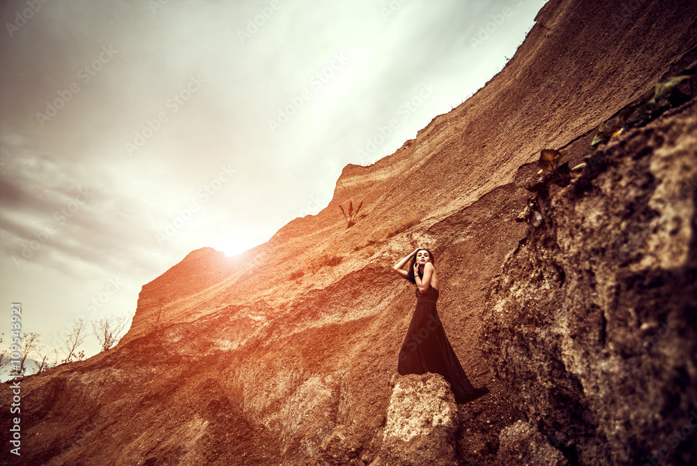 Woman in long black dress on the sand canyon