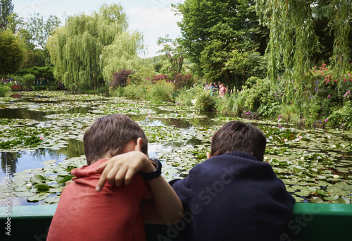 Rear view of two young brothers looking down from footbridge to lily pond photo