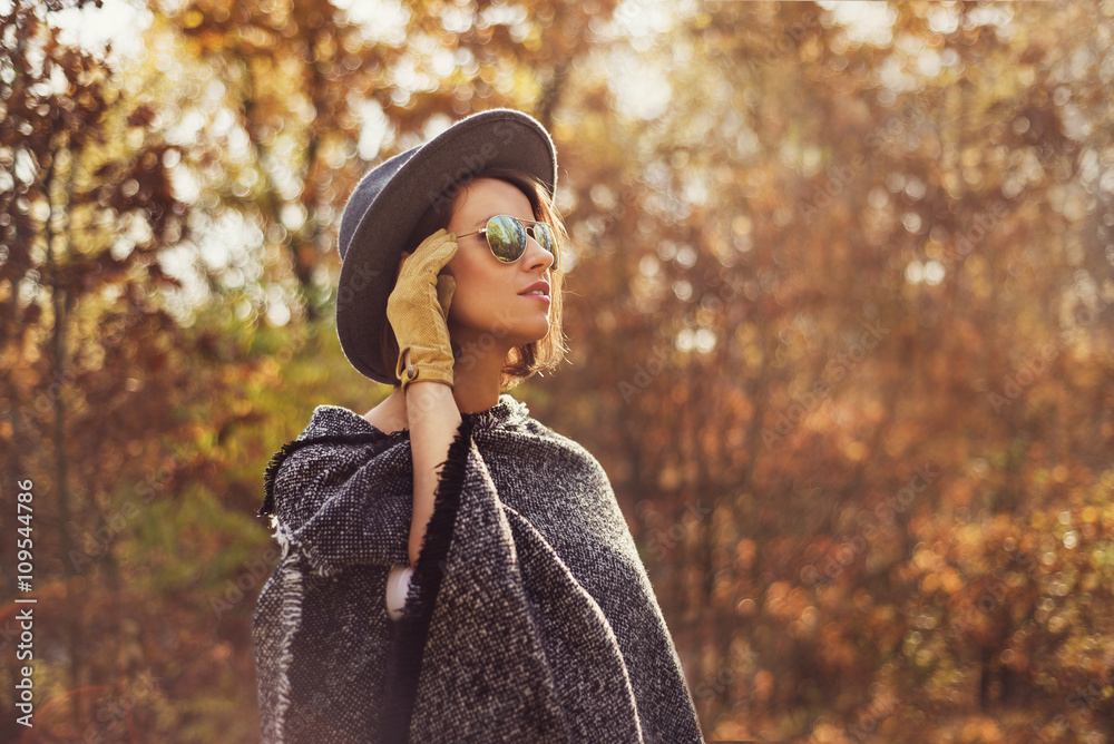 Naklejka premium Portrait of a young, elegant woman looking away from the camera. Photogaph taken in autumn surrounding.