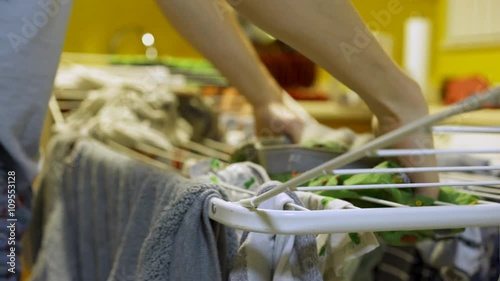 Male standing in kitchen hanging clothes on dryer rack after doing his laundry.
 photo