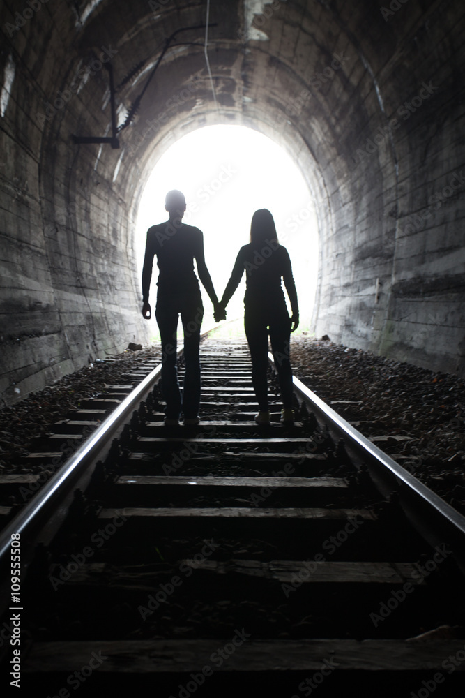 Couple walking together through a railway tunnel