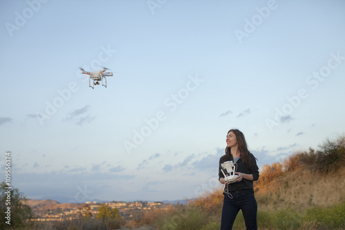 Female commercial operator flying drone looking up smiling, Santa Clarita, California, USA photo