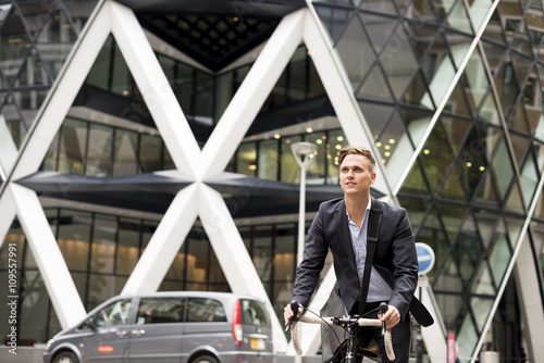 Businessman on bike, 30 St Mary Axe in background, London, UK photo