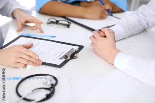Two doctors and male patient discussing medical history at the table, close up