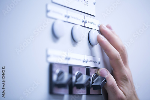 Cropped view of young mans hand adjusting dial on switchgear photo