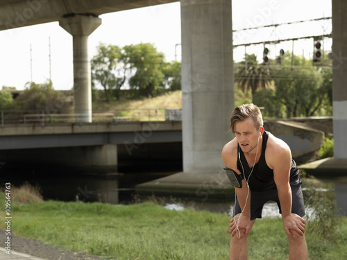 Young man beside river, taking a break from exercise