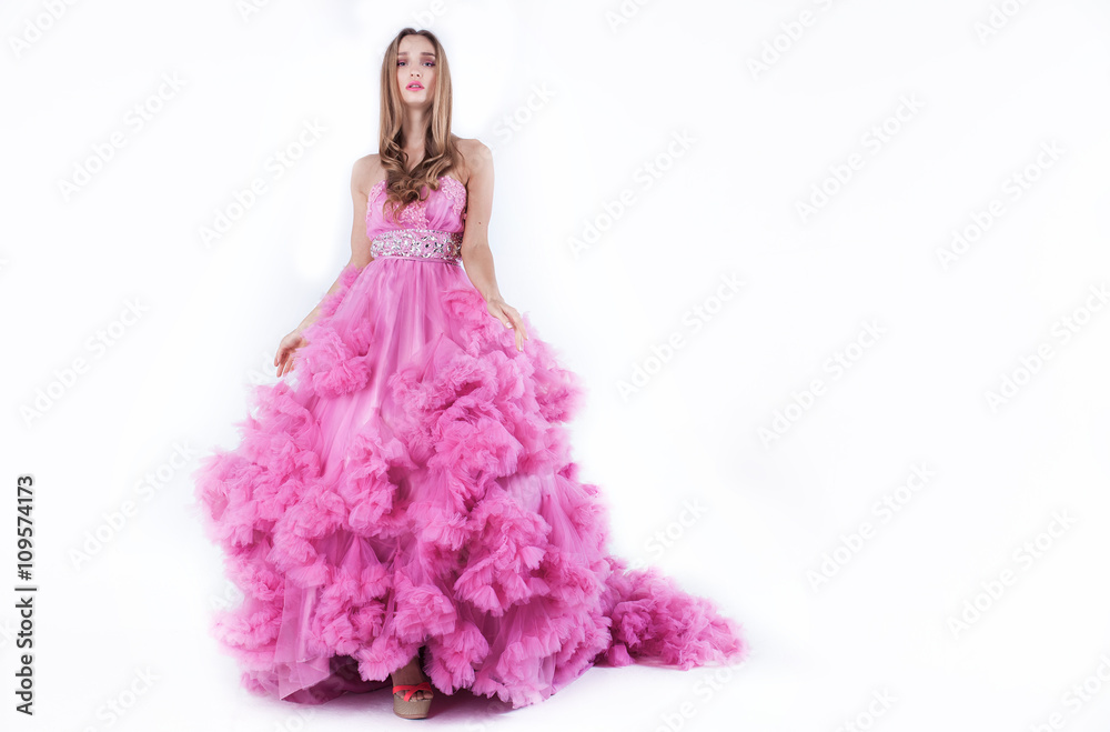 Portrait of young beautiful caucasian blonde in gorgeous pink dress on white background