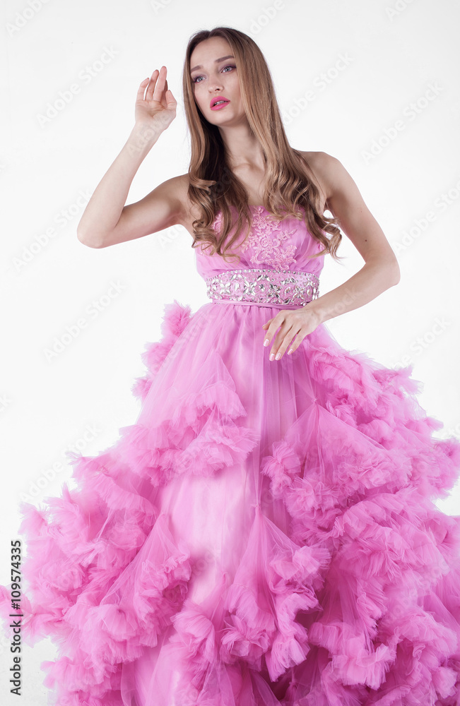Naklejka premium Portrait of sexy young beautiful caucasian blonde in gorgeous pink dress on white background