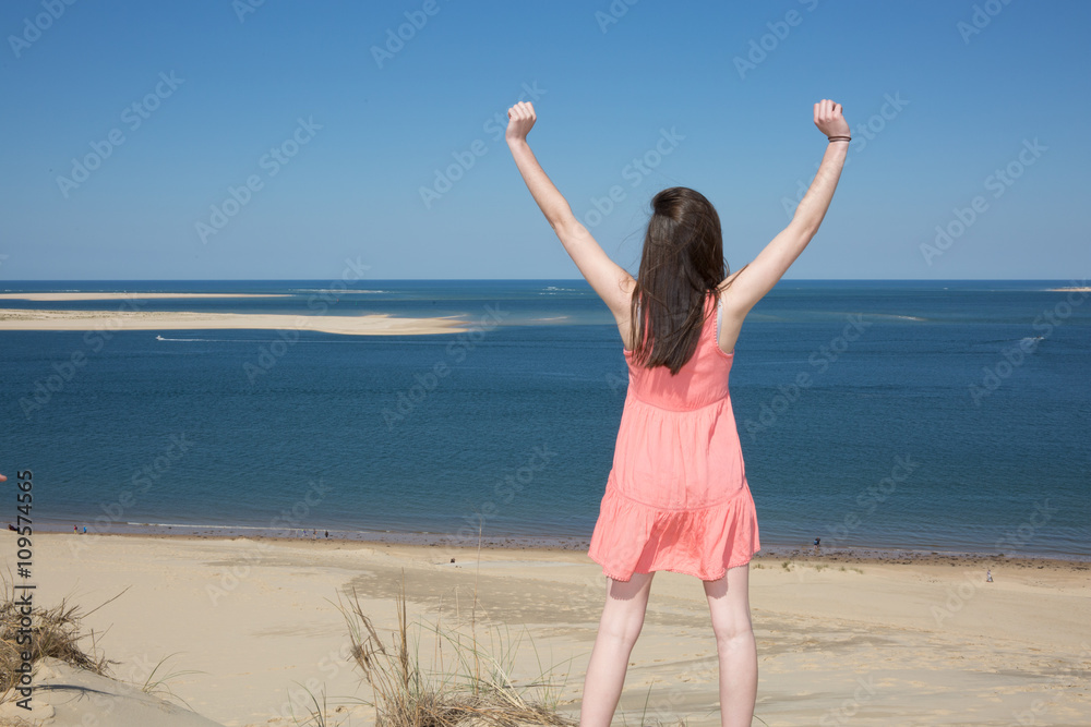 Happy woman enjoying relaxing breeze and freedom by the sea. Joyful asian girl raising arms to the sky. Happy woman enjoying relaxing breeze and freedom by the sea. Joyful asian girl raising arms to the sky.
