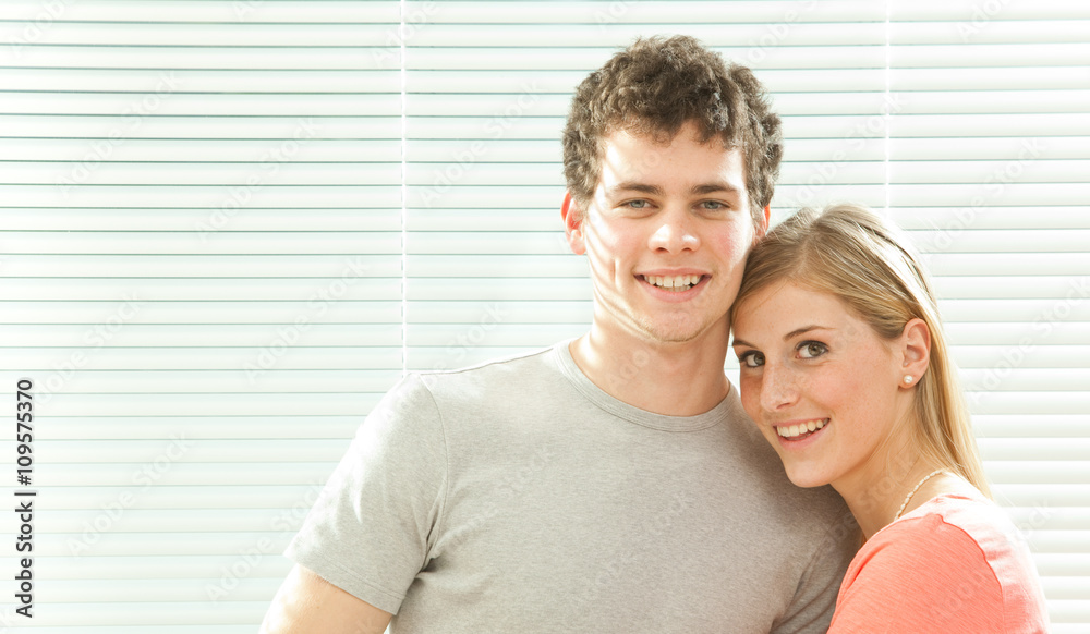 Young casual couple in love with venetian blind window background Young casual couple in love with venetian blind window background