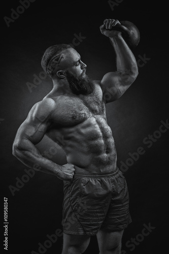 Bodybuilder with a beard lifts a heavy kettlebell