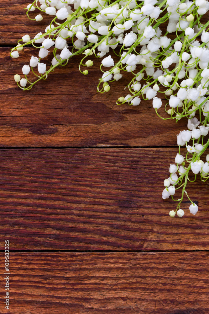white flowers lilies of the valley scattered on the old wooden brown background. with space for text white flowers lilies of the valley scattered on the old wooden brown background. with space for text