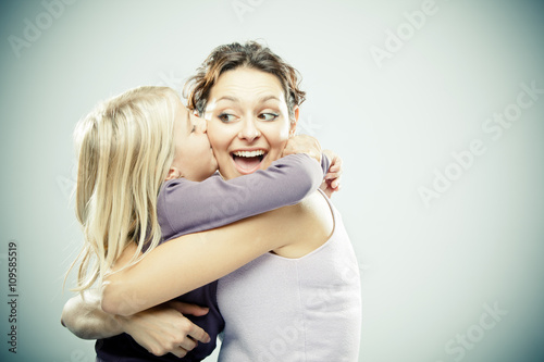 Beautiful brunette woman with young blond girl on grey background