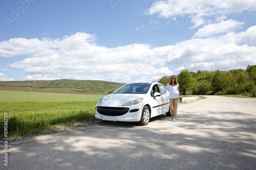 Smiling mature woman with her broken down car