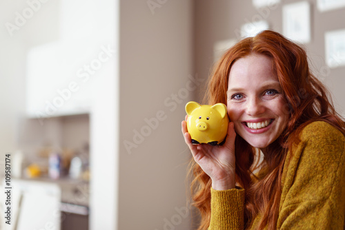 lachende frau hält sparschwein in der hand photo