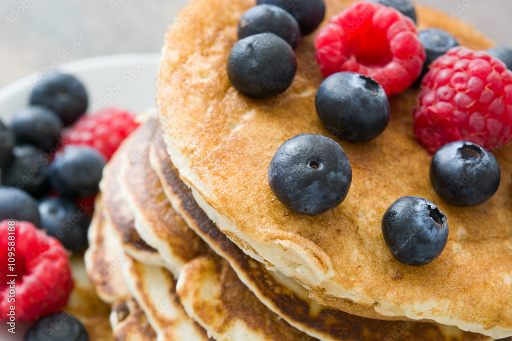 Pancakes with blueberries and raspberries on rustic wood
