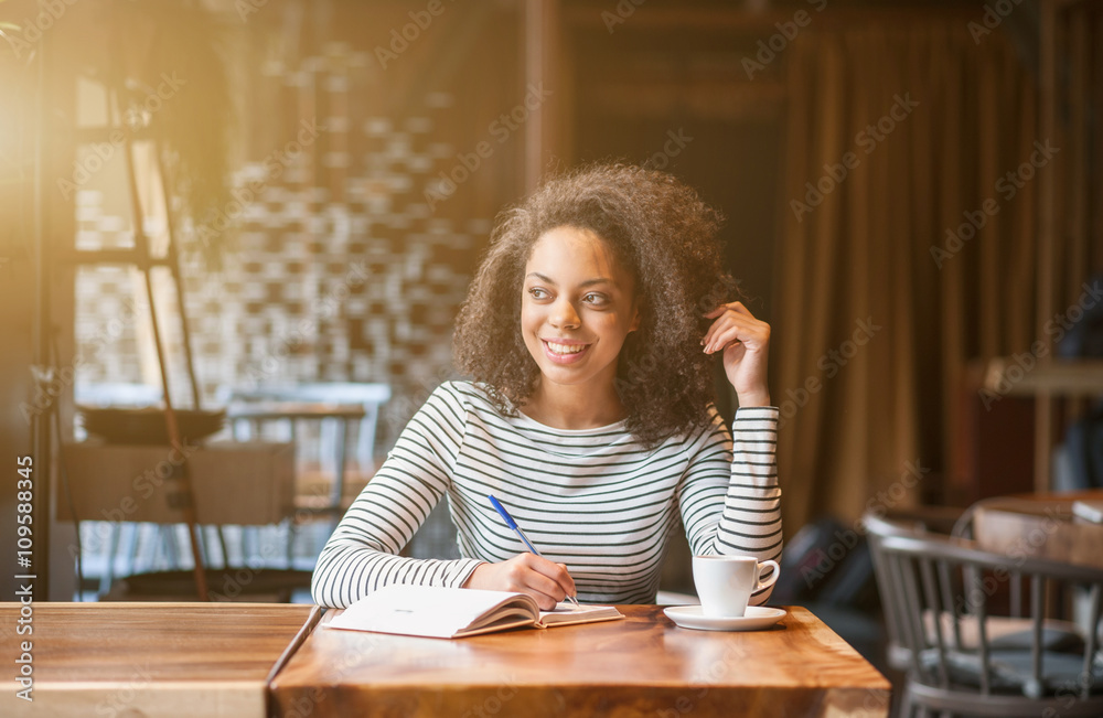 Attractive african girl is making notes in cafeteria Attractive african girl is making notes in cafeteria