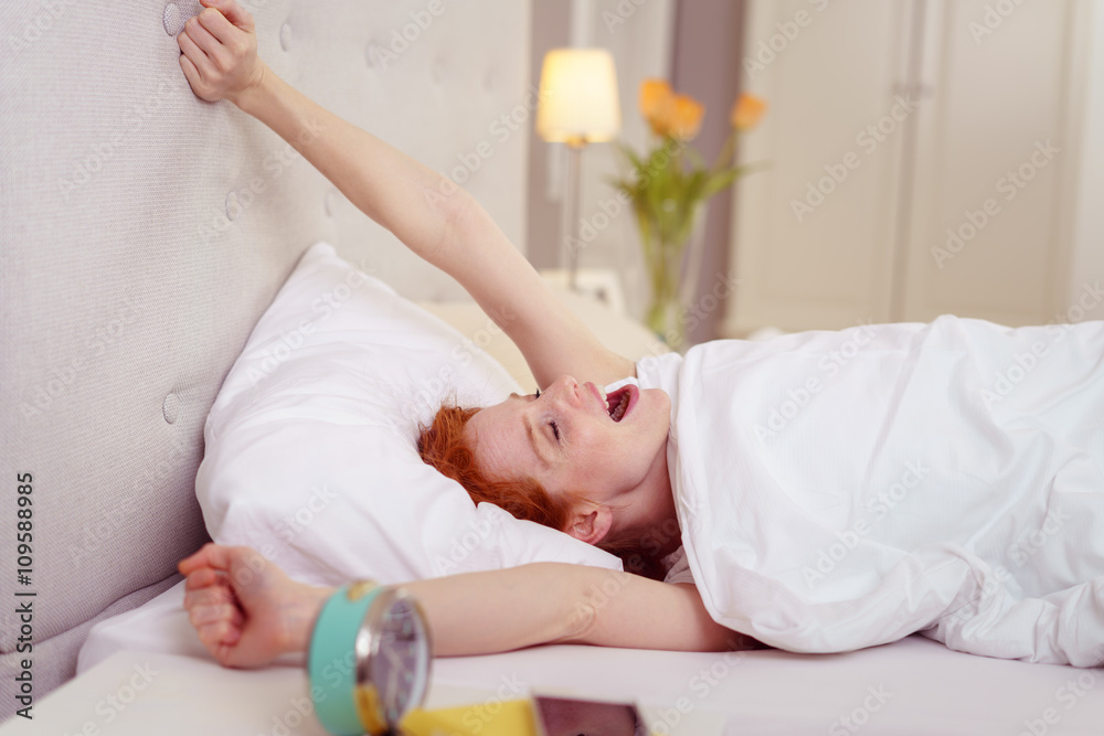 frau streckt sich am morgen im bett frau streckt sich am morgen im bett
