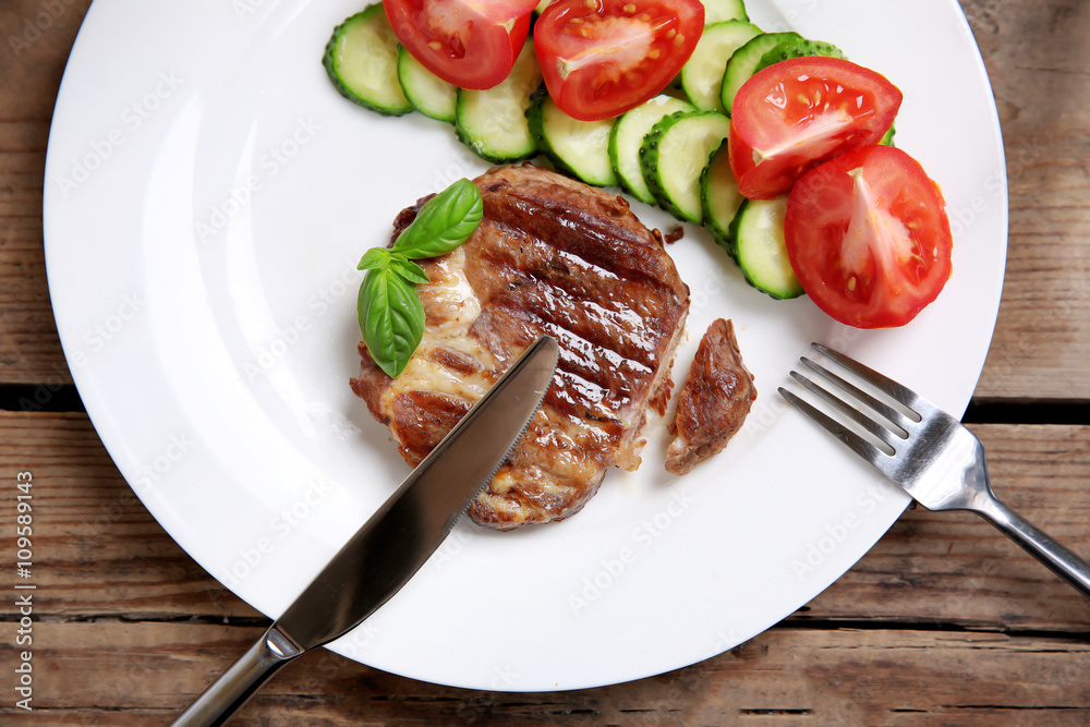 Roasted beef fillet and fresh vegetables on plate, on wooden background Roasted beef fillet and fresh vegetables on plate, on wooden background