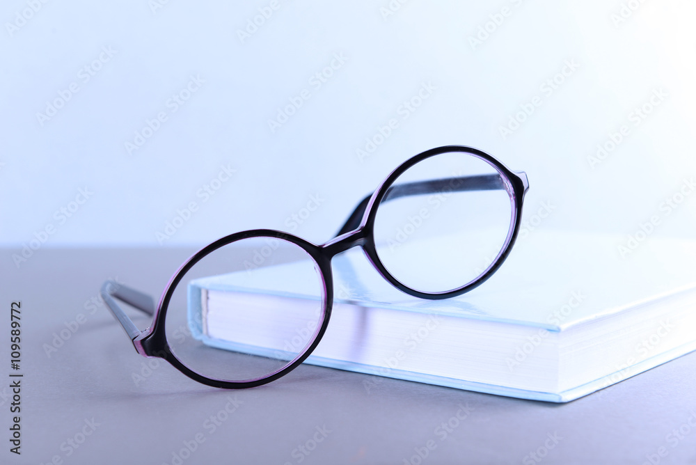 Books and eyeglasses on grey table against blue wall Books and eyeglasses on grey table against blue wall