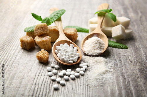 Pile of brown sugar cubes and stevia  on grey wooden background photo