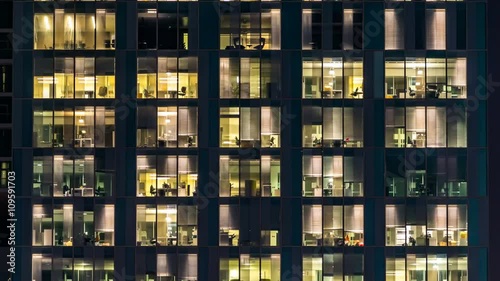 window of the multi-storey building of glass and steel lighting and people within timelapse