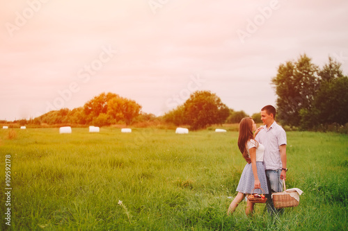 Man and woman stay with berries basket on sunset meadow