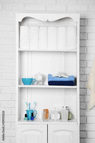 Bathroom set with towels  toothbrushes and sponges on a shelf in light interior