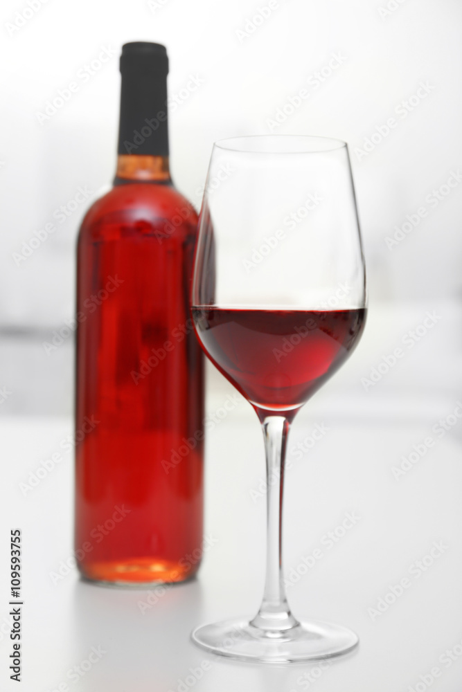 Glass of red wine with bottle on blurred interior background Glass of red wine with bottle on blurred interior background