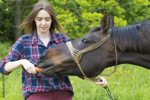 Teenager girl is feeding her horse pet