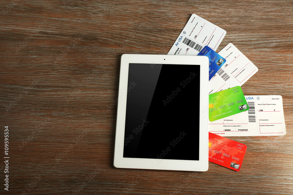 Tablet with credit cards and flight tickets on wooden table Tablet with credit cards and flight tickets on wooden table