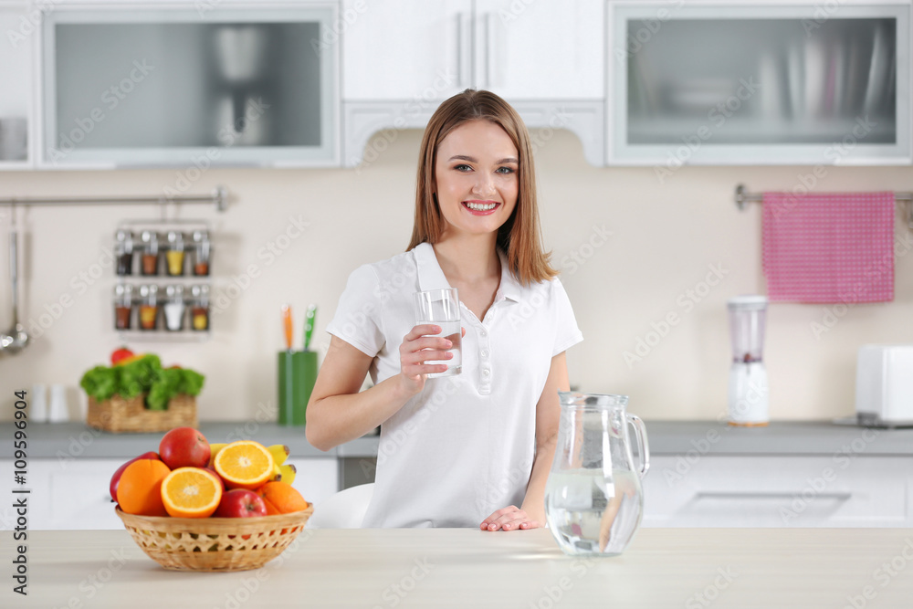 Young woman drinking water from glass in the kitchen