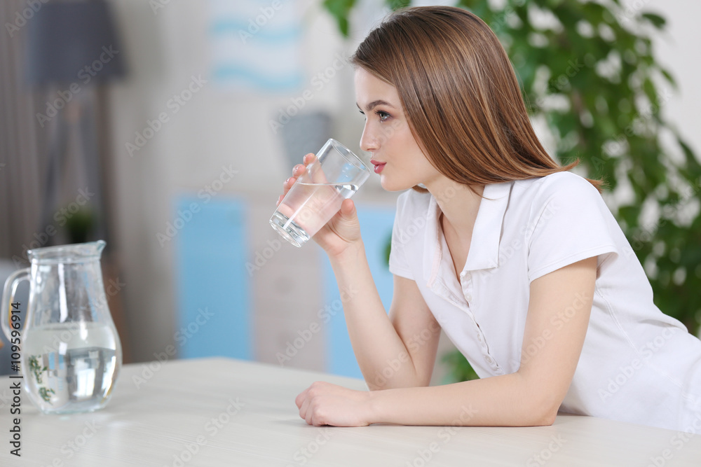 Young woman drinking water from glass in the kitchen Young woman drinking water from glass in the kitchen
