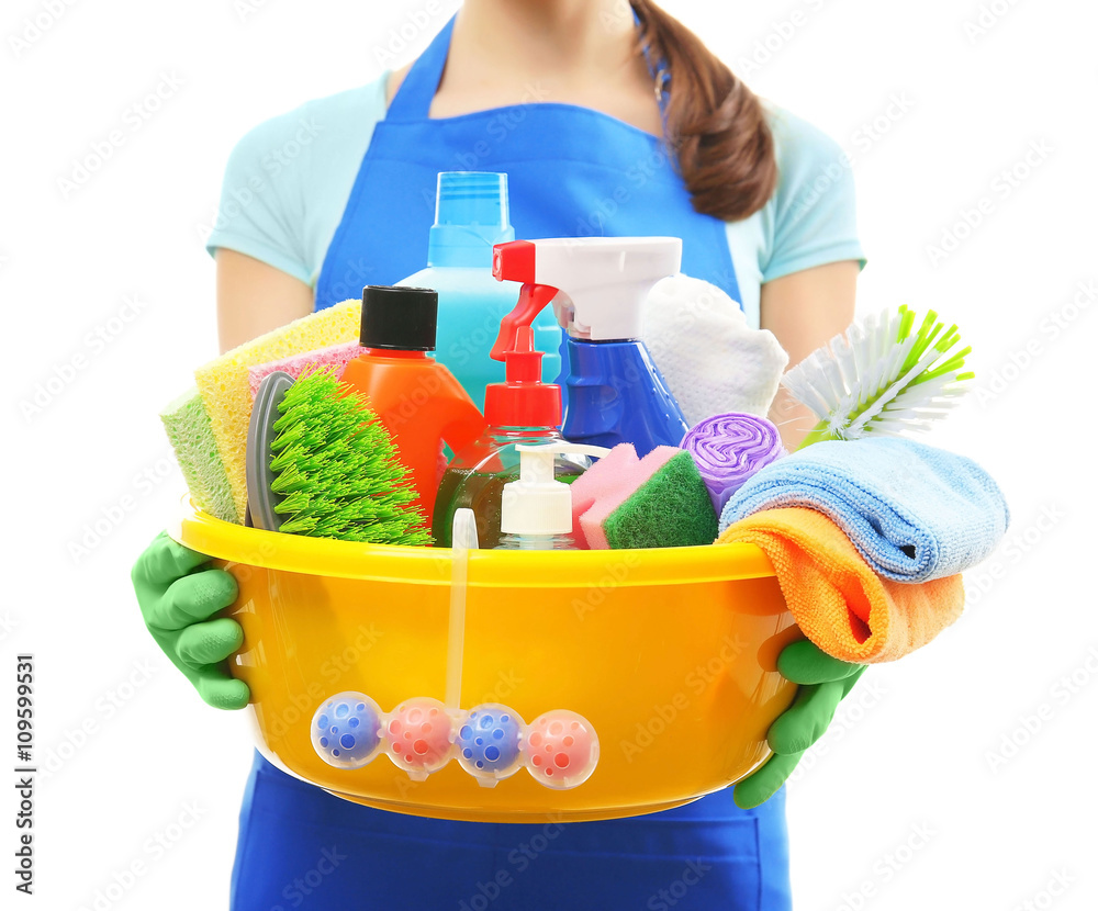 Young woman holding cleaning tools and products in tub, isolated on white Young woman holding cleaning tools and products in tub, isolated on white