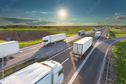 Big white trucks on highway at idyllic sunny morning