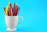 Colorful stationery in white cup on blue background