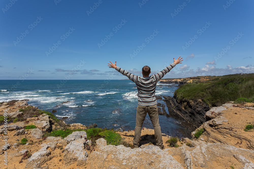 Obraz premium Tourist man on the rocky shore of sea.